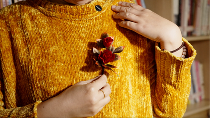 Woman wearing red velvet flower rose brooch on yellow top - styling example